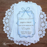 Boy baby shower favor bags adorned with a blue bow and frame printed on white paper bags.  Each is personalized with 'Babies are Sweet enjoy a treat, thank you for making my day complete'.  Mother to be's name and event date also printed.