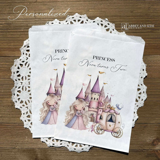 Princess Party Candy Bags printed on white paper bags and personalized with 'PRINCESS (your name) turns (your age). Adorned with a sweet princess standing in front of her castle and carriage, all in hints of pink and purple. Bags are larger than most and will fit all kinds of fun goodies.
