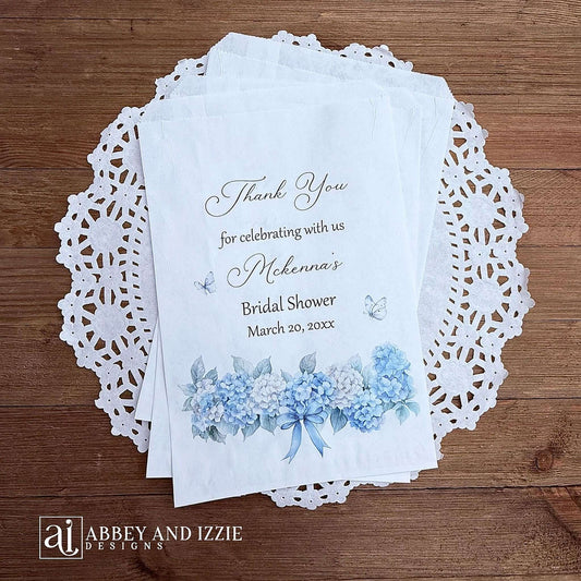 Personalized blue hydrangea bridal shower favors bags, perfect for a small gift of appreciation or a cookie bar or even a candy bar. White bags adorned with delicate blue hydrangeas for a sweet addition to your event.