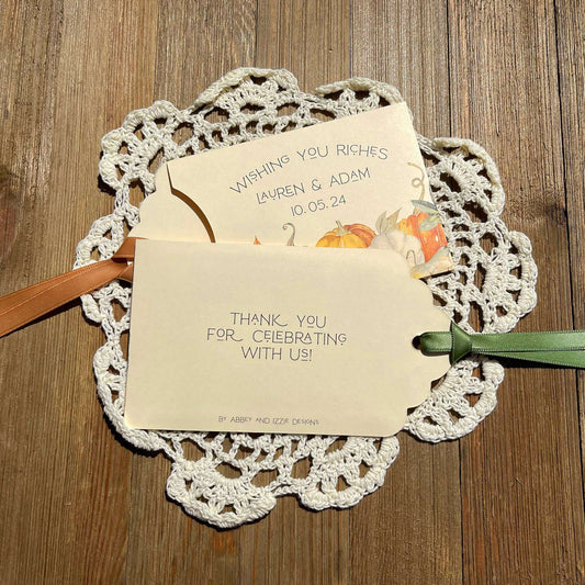 Unique Fall Wedding Guest Favors, Ivory lottery ticket envelopes for a fall wedding, personalized for the bride and groom. Each comes with moss green or gold ribbon attached, adorned with a fall scene. Slide a lottery ticket in to see who wins.