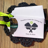 Personalized Pickleball Party Favors that will be fun for all your guests. Adonred with a pickleball and paddles these are personalized for the event. Printed on white cardstock with green ribbon attached. Slide a lottery ticket in the open end and see who wins.