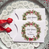 Personalized Christmas Party Favors adorned with a beautiful wreath and a red ribbon attached.  These can be used for lottery ticket favors or gift card holders.