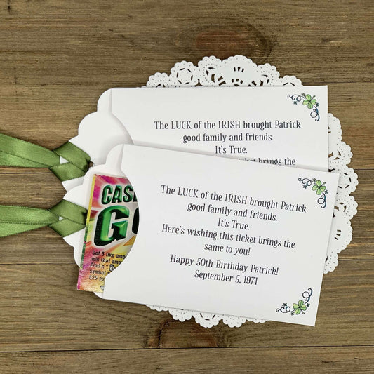Irish Birthday Party Favors printed with 'the luck of the Irish' and the honoree name and birth date. Lottery ticket envelopes printed on white card stock adorned with a green ribbon and shamrocks.