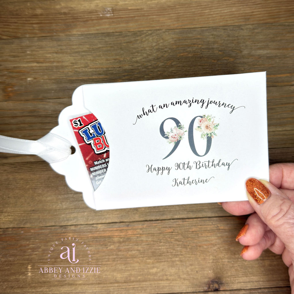 Elegant 90th Birthday Party Favors will add a special touch to your event.  Printed on white card stock with a large 90 in floral font add the guest of honors name for a personal touch.  Your choice of pink, black or white ribbon which comes attached