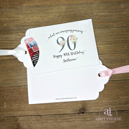 Elegant 90th Birthday Party Favors will add a special touch to your event.  Printed on white card stock with a large 90 in floral font add the guest of honors name for a personal touch.  Your choice of pink, black or white ribbon which comes attached