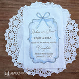 Boy baby shower favor bags adorned with a blue bow and frame printed on white paper bags.  Each is personalized with 'Babies are Sweet enjoy a treat, thank you for making my day complete'.  Mother to be's name and event date also printed.  