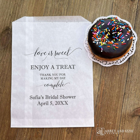 Our personalized glassine bridal shower favor bags are perfect for a candy bar, cookie bar, donut bar or brownies.  Each translucent bag comes printed with 'love is sweet enjoy a treat thank you for making my day complete.'  Personalized with the brides name and event date.  Bags are glassine and grease resistant.