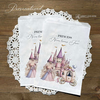 Princess Party Candy Bags printed on white paper bags and personalized with 'PRINCESS (your name) turns (your age).  Adorned with a sweet princess standing in front of her castle  and carriage, all in hints of pink and purple.  Bags are larger than most and will fit all kinds of fun goodies.