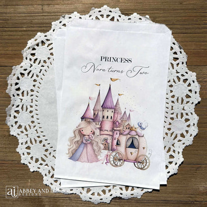 Princess Party Candy Bags printed on white paper bags and personalized with 'PRINCESS (your name) turns (your age).  Adorned with a sweet princess standing in front of her castle  and carriage, all in hints of pink and purple.  Bags are larger than most and will fit all kinds of fun goodies.