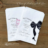 Send your guests home with a memorable keepsake from the bride-to-be's special day with our She's Tying the Knot Bridal Shower Favor Bags . These charming favor bags feature a playful "She's Tying the Knot" design that perfectly captures the excitement of bridal shower celebrations.  Adorned with a black or Pink bow, your choice and personalized for the bride to be.  Printed on white bags, larger than most.