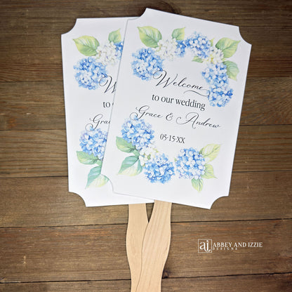 Elevate your wedding ambiance with our personalized blue hydrangea fans, beautifully crafted to complement your special day.  Printed on white card stock with 'welcome to our wedding' and the bride and grooms names with wedding date printed. 