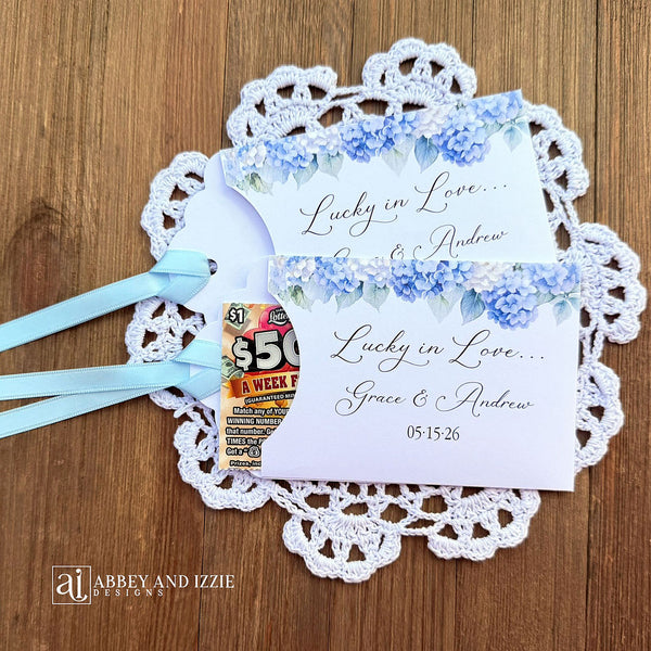 Our blue hydrangea wedding favors are made from white cardstock, adorned with delicate hydrangeas at the top, printed with 'Lucky In Love' with the brdie and grooms names and wedding date.  Each comes with a light blue ribbon attached for an elegant touch.  Guest will find these lotto favors fun with hopes of winning something big.  