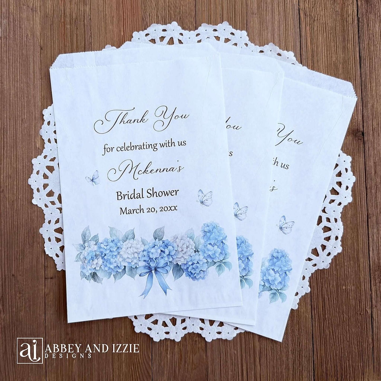 Personalized blue hydrangea bridal shower favors bags, perfect for a small gift of appreciation or a cookie bar or even a candy bar.  White bags adorned with delicate blue hydrangeas for a sweet addition to your event.
