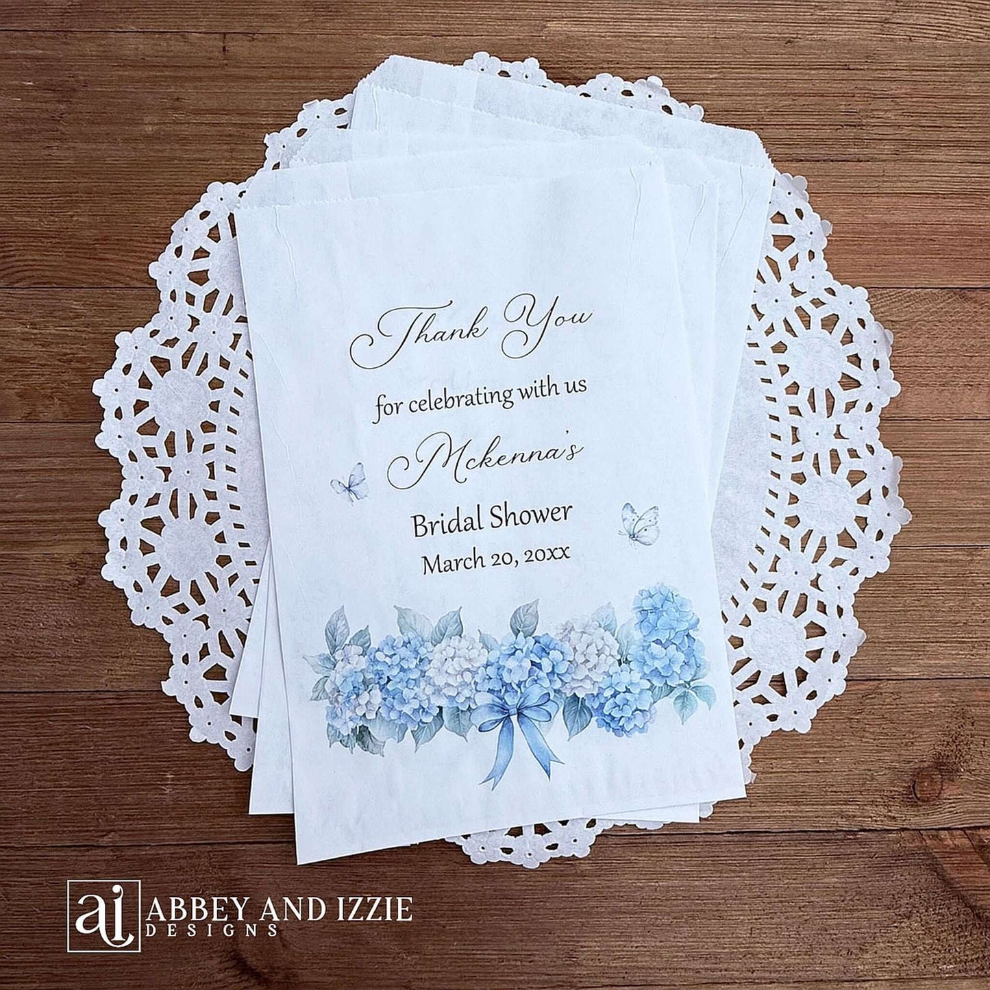 Personalized blue hydrangea bridal shower favors bags, perfect for a small gift of appreciation or a cookie bar or even a candy bar.  White bags adorned with delicate blue hydrangeas for a sweet addition to your event.