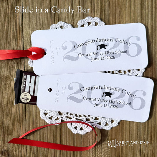 Graduation Candy Bar Favors personalized for the graduate. Printed on white card stock, choice of ribbon color.  Class of year printed in large font and congratulations to the guest of honor with school name and event date.  Just slide a candy bar in the open end and tie the ribbon on.