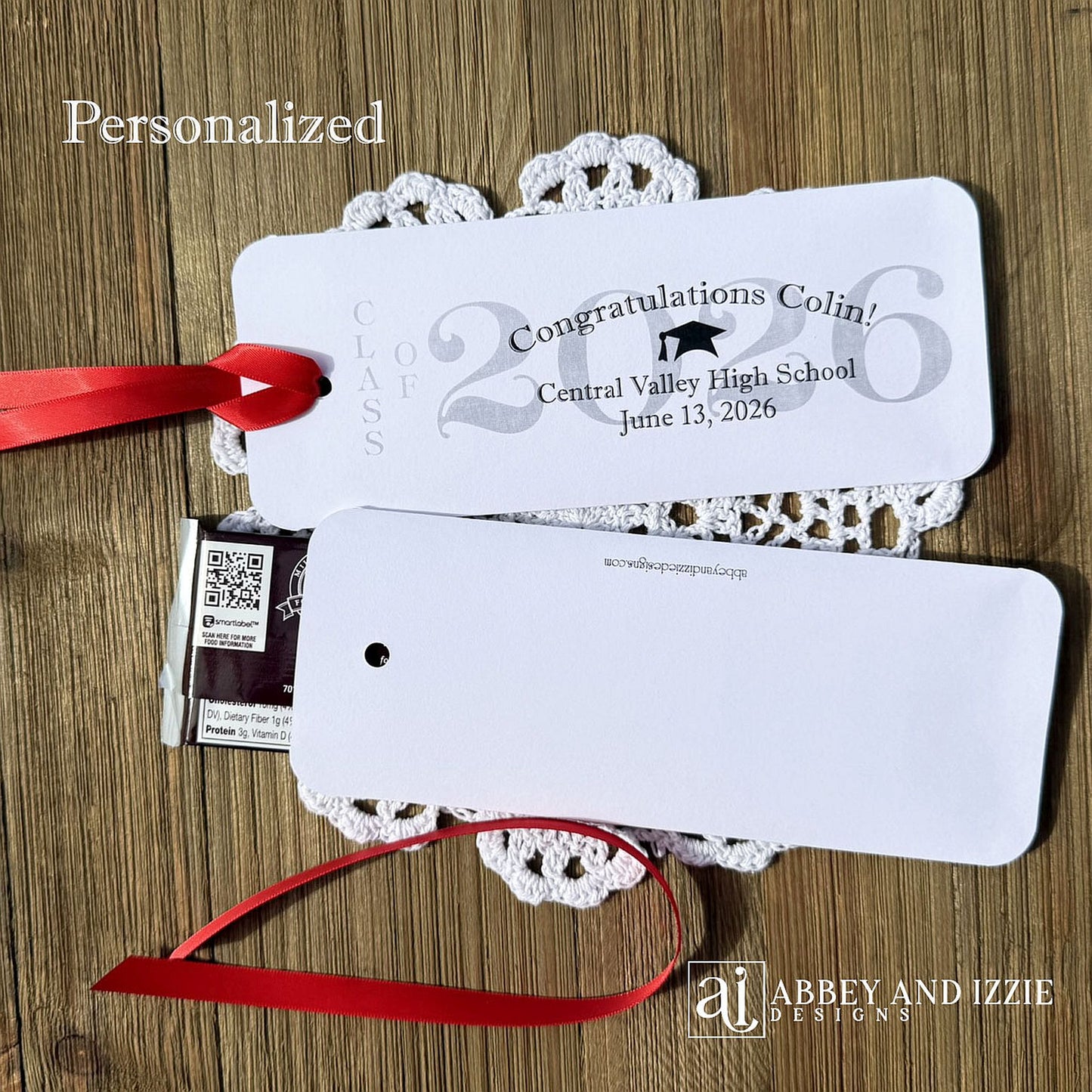 Graduation Candy Bar Favors personalized for the graduate. Printed on white card stock, choice of ribbon color.  Class of year printed in large font and congratulations to the guest of honor with school name and event date.  Just slide a candy bar in the open end and tie the ribbon on.