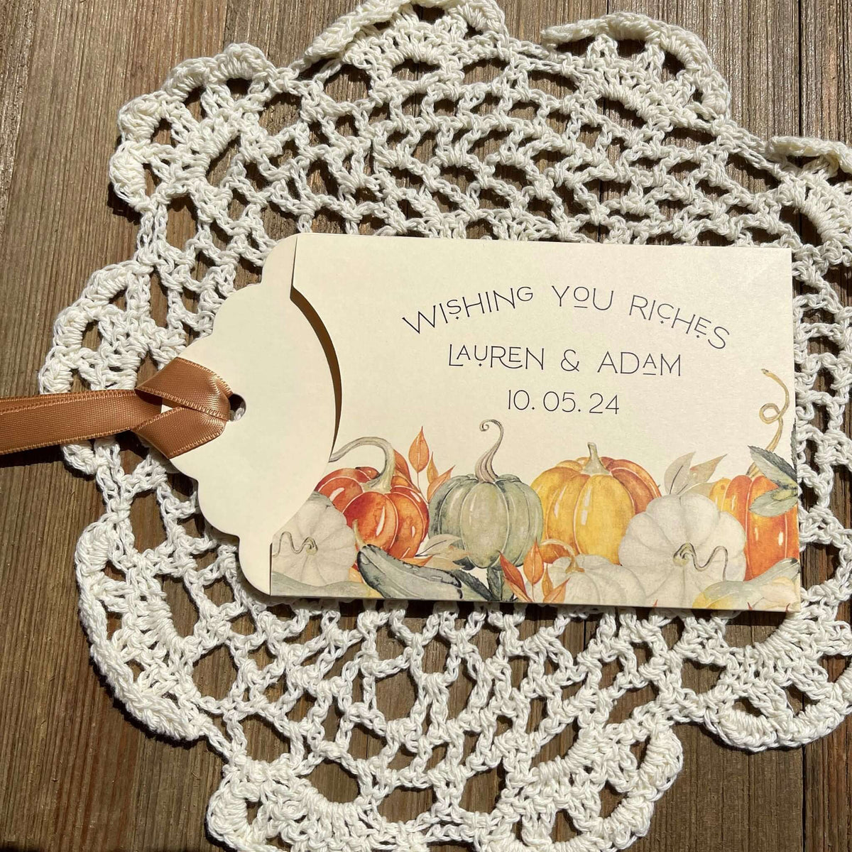 Ivory lottery ticket envelopes for a fall wedding, personalized for the bride and groom.  Each comes with moss green or gold ribbon attached, adorned with a fall scene.  Slide a lottery ticket in to see who wins.