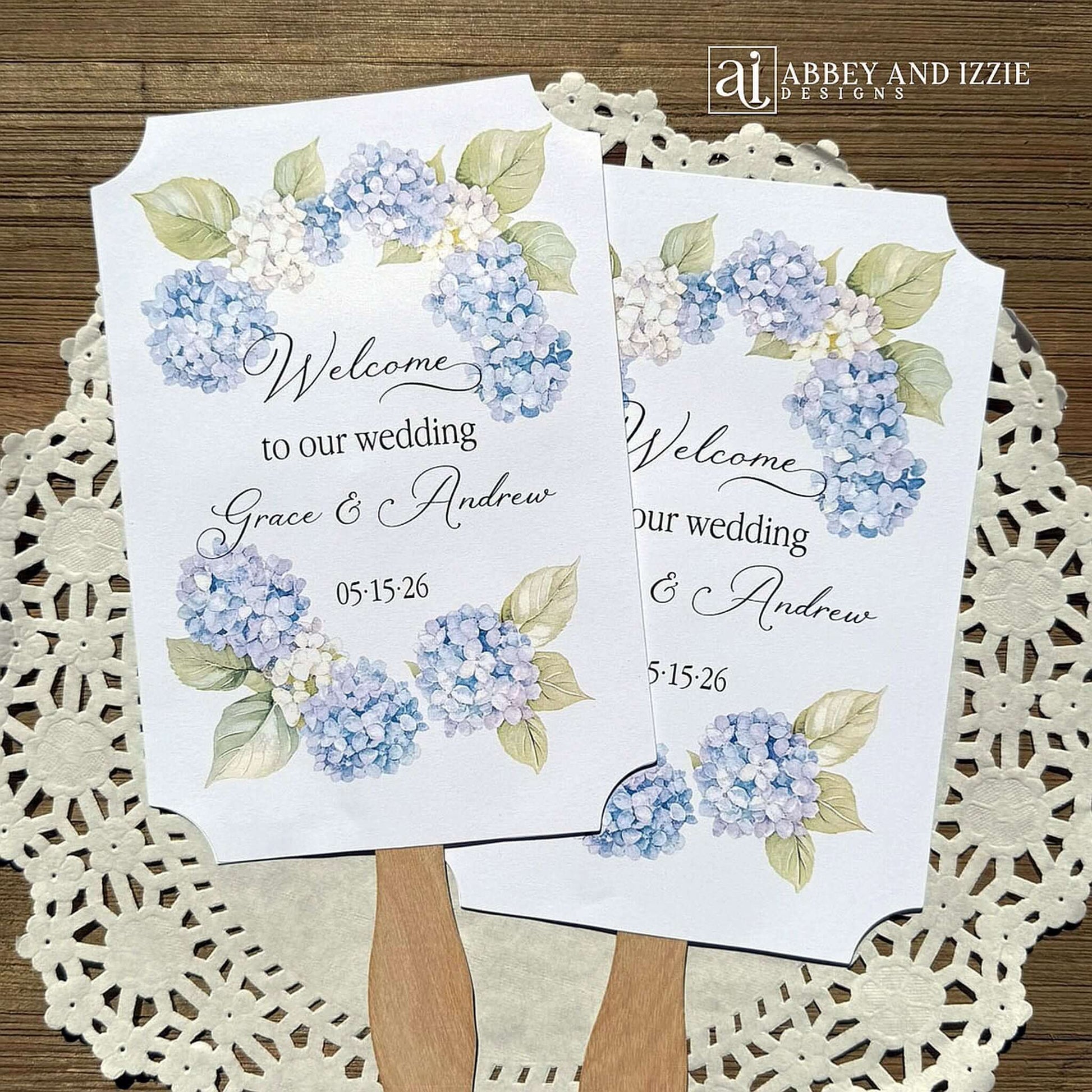 Elevate your wedding ambiance with our personalized blue hydrangea fans, beautifully crafted to complement your special day.  Printed on white card stock with 'welcome to our wedding' and the bride and grooms names with wedding date printed.  Fans ship assembled to you and are two sided, printing on one side only, handle hidden between the layers for a finished look. 