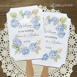 Elevate your wedding ambiance with our personalized blue hydrangea fans, beautifully crafted to complement your special day.  Printed on white card stock with 'welcome to our wedding' and the bride and grooms names with wedding date printed.  Fans ship assembled to you and are two sided, printing on one side only, handle hidden between the layers for a finished look. 