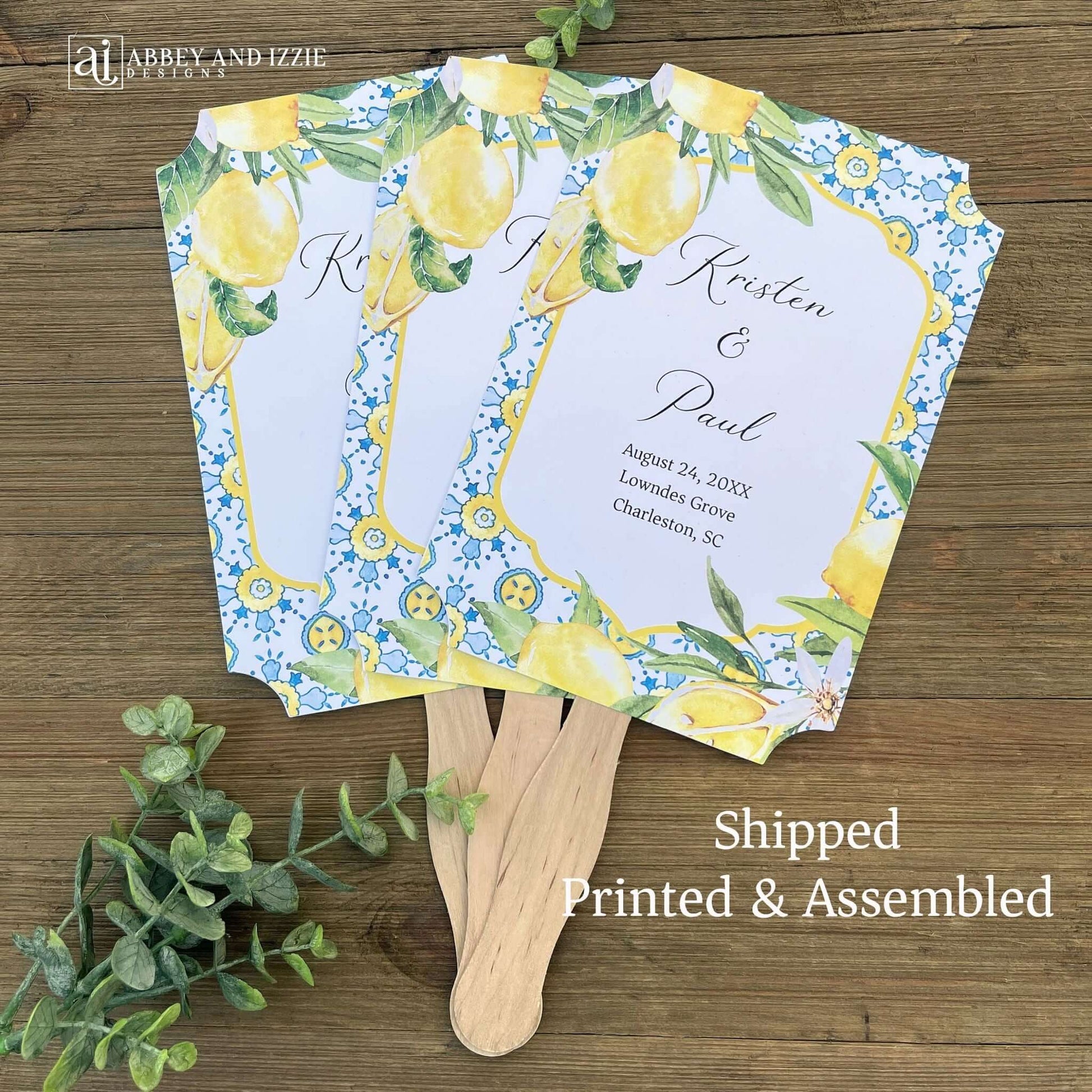 Mediterranean Wedding Program Fans, adorned with blue tiles and lemons. Printed on white card stock, two sided with handle hidden between. Wedding program on the back on the fans, front is personalized for the bride and groom.