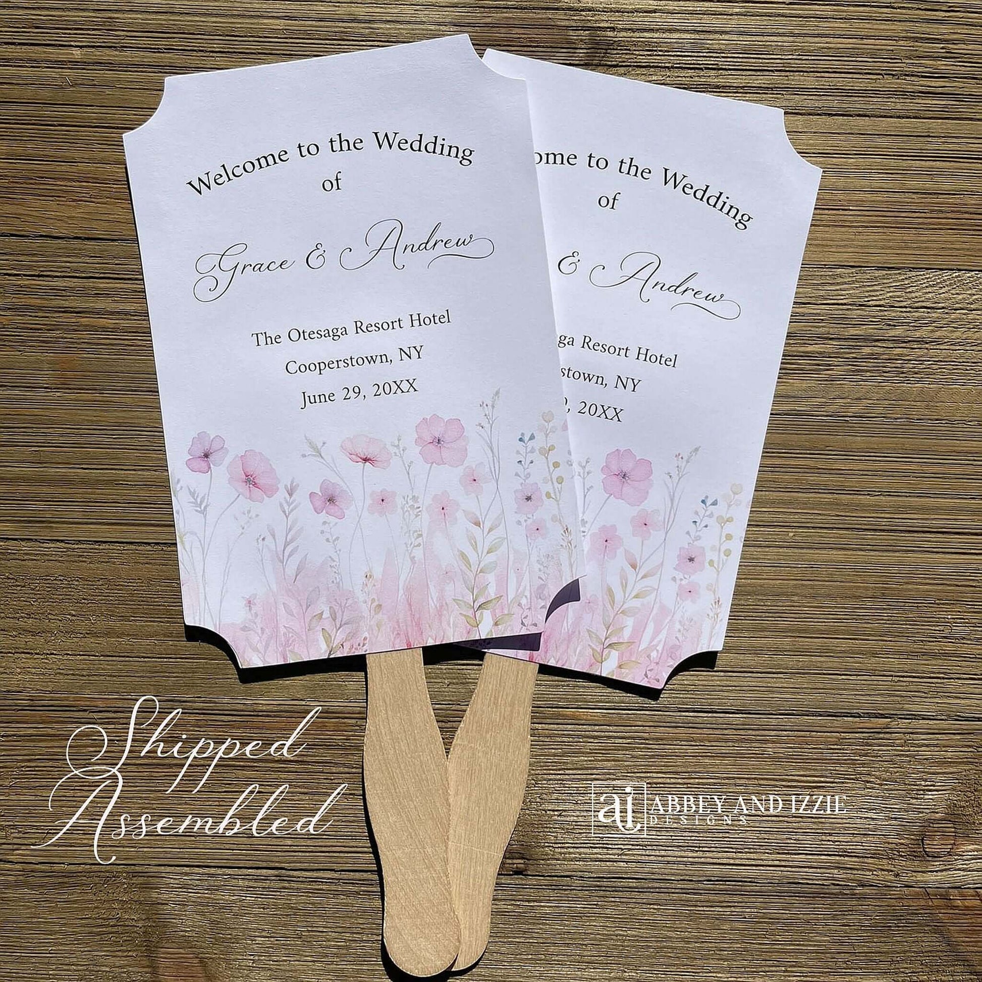 Blush pink wedding fans personalized, printed on white card stock with soft pink flower at the bottom.  Fans are personalized for the bride and groom and includes, place, city, state and date of your wedding.  They arrive fully assembled and ready for your day.