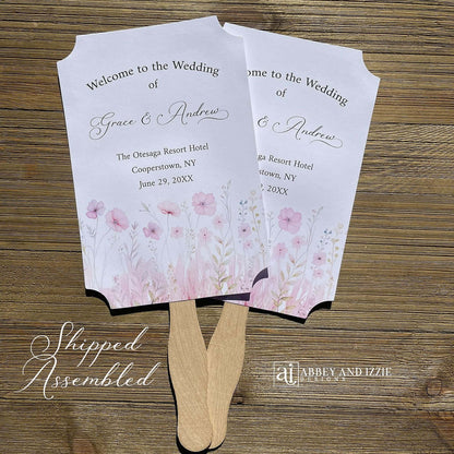 Blush pink wedding fans personalized, printed on white card stock with soft pink flower at the bottom.  Fans are personalized for the bride and groom and includes, place, city, state and date of your wedding.  They arrive fully assembled and ready for your day.