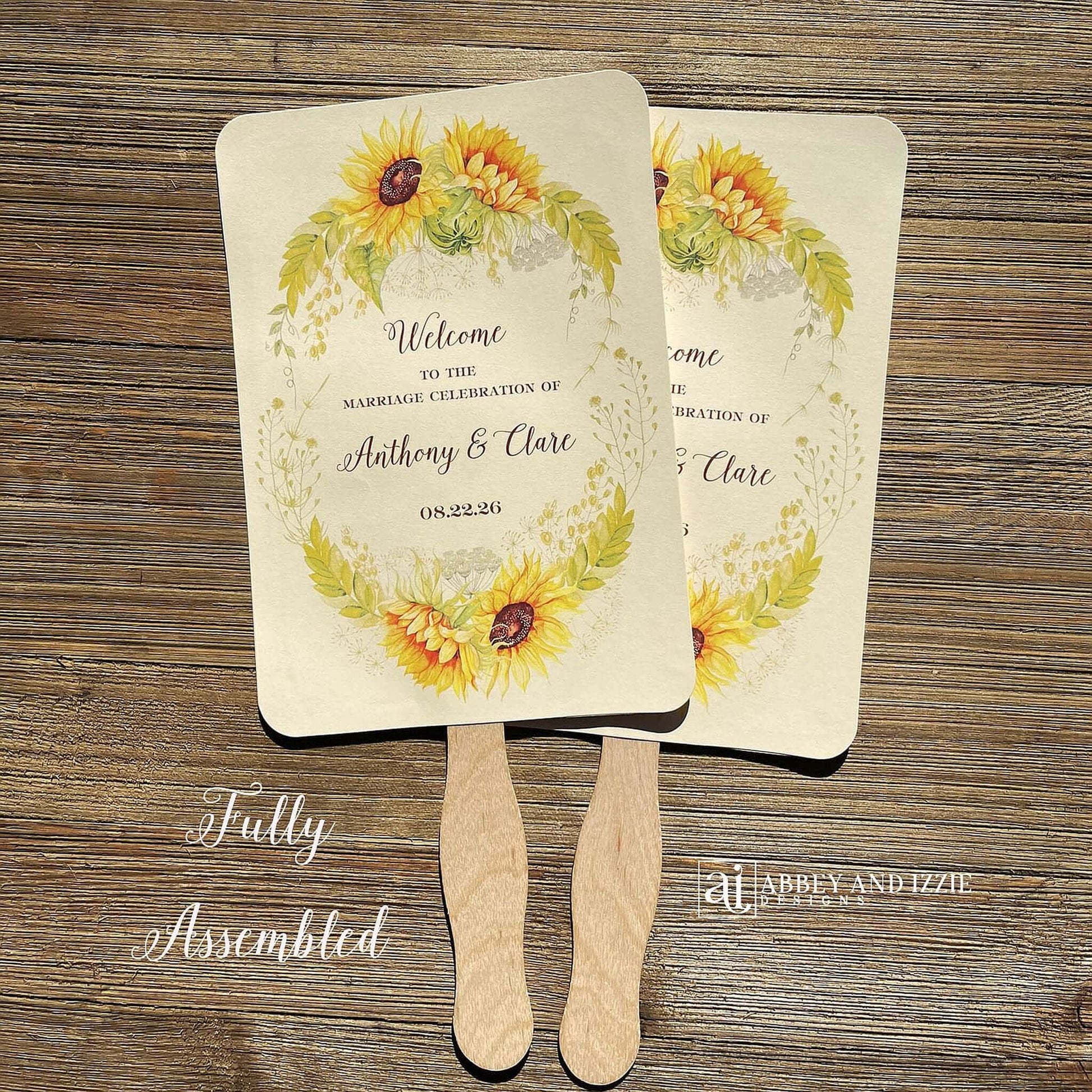 Sunflower Wedding Hand Fans Personalized , personalized for the bride and groom and adorned with a ring of sunflowers.  Fans are printed on ivory cardstock, two sided so handle is hidden between.  Wedding fans ship fully assembled and ready for your big day.