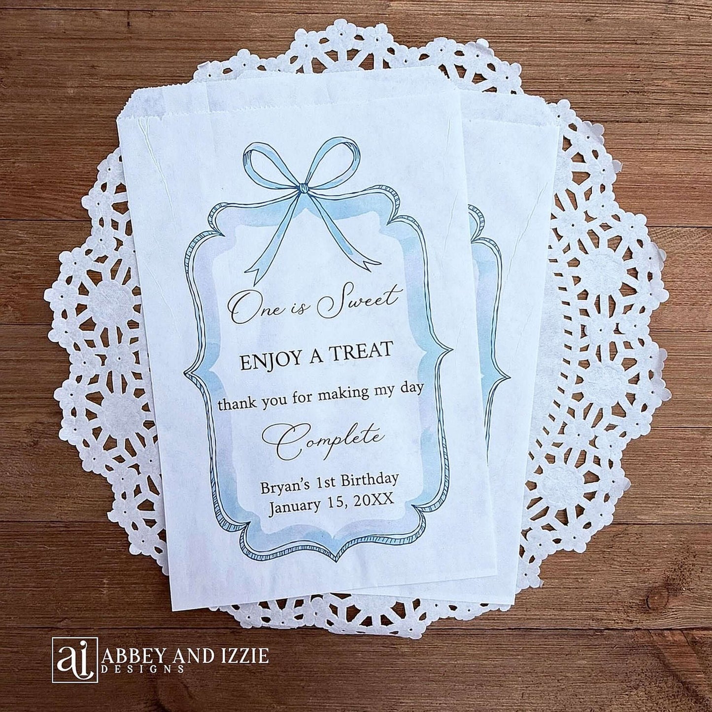 Personalized first birthday party favor bags, 'one is sweet, enjoy a treat, thank you for making my day complete'.  Printed on white paper bags and adorneed with a blue bow and border these will add a touch of elegance to the treat table. 
