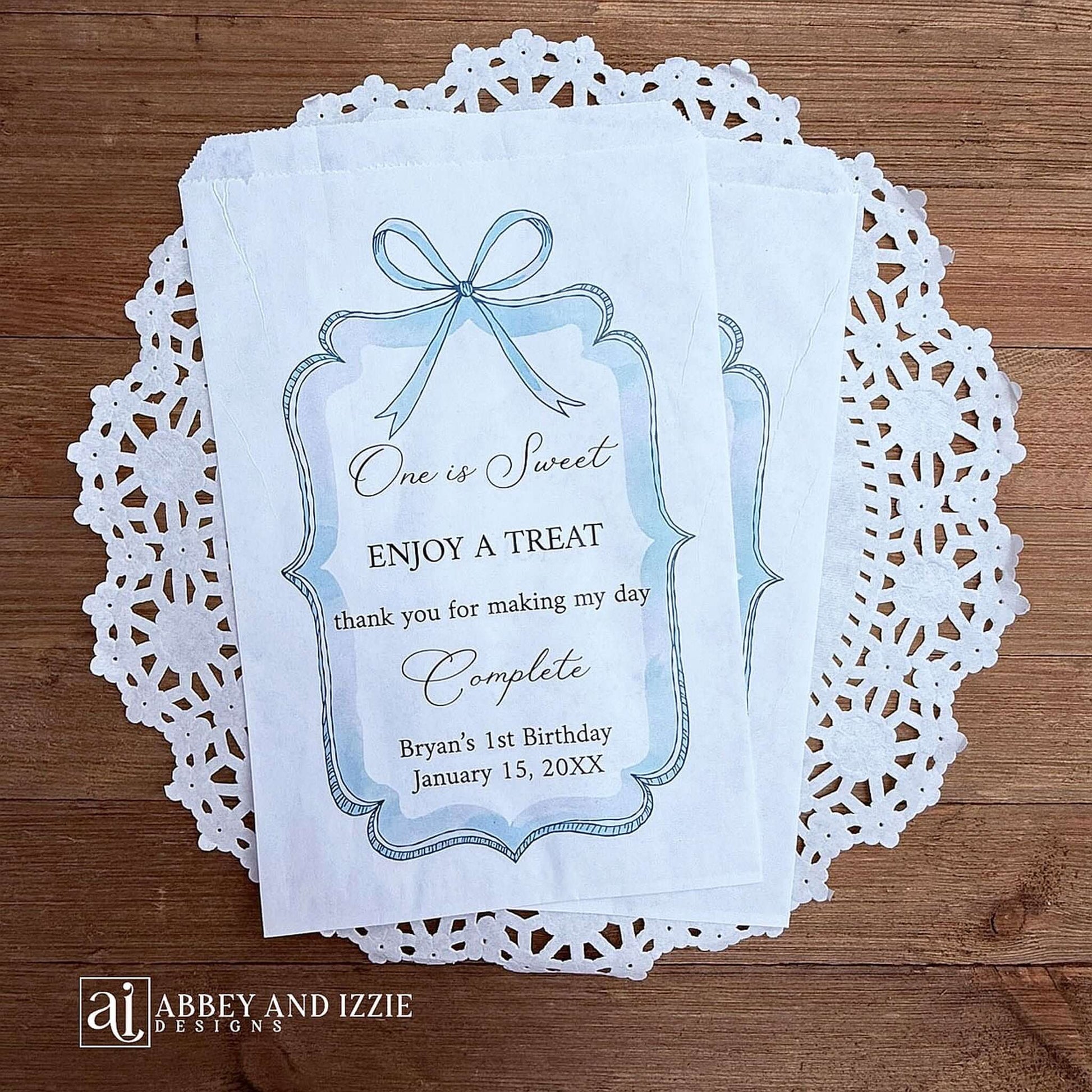 Personalized first birthday party favor bags, 'one is sweet, enjoy a treat, thank you for making my day complete'.  Printed on white paper bags and adorneed with a blue bow and border these will add a touch of elegance to the treat table. 
