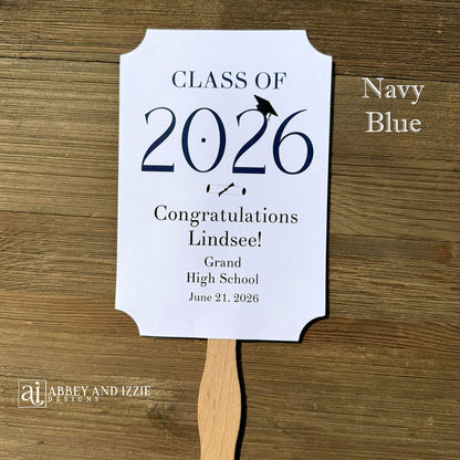  Personalized Graduation Fansto keep guest cool and a fun keepsake to take home. Each printed on white card stock, ship fully assembled, two sided with handle hidden between.  Your choice of year color.