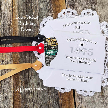 Lottery Ticket Birthday Favors, slide a lottery ticket in these cute envelopes for a fun favor.  Printed with 'still winning at' with your birthday number and year.  Printed on white card stock with your choice of ribbon color.