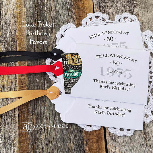 Lottery Ticket Birthday Favors, slide a lottery ticket in these cute envelopes for a fun favor.  Printed with 'still winning at' with your birthday number and year.  Printed on white card stock with your choice of ribbon color.