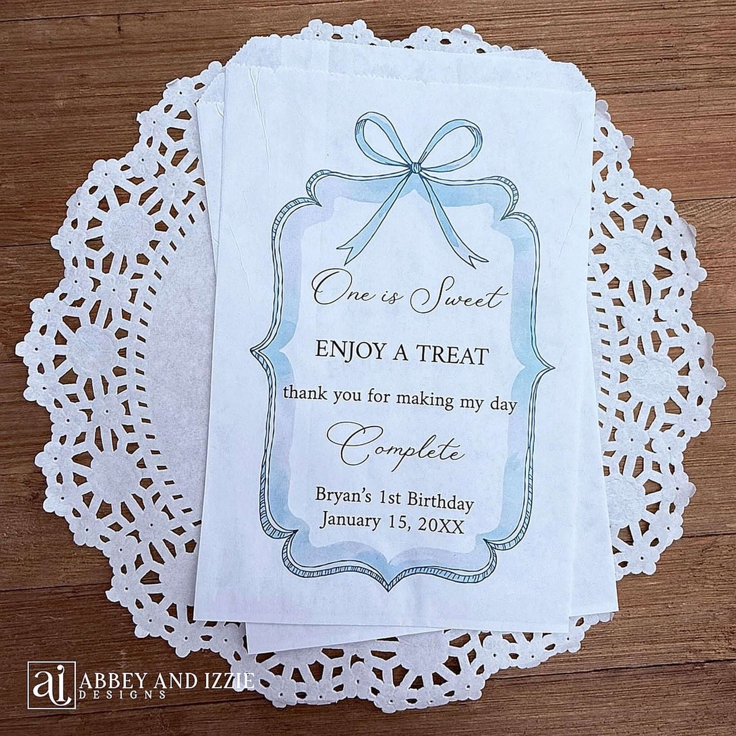 Personalized first birthday party favor bags, 'one is sweet, enjoy a treat, thank you for making my day complete'.  Printed on white paper bags and adorneed with a blue bow and border these will add a touch of elegance to the treat table. 
