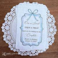 Personalized first birthday party favor bags, 'one is sweet, enjoy a treat, thank you for making my day complete'.  Printed on white paper bags and adorneed with a blue bow and border these will add a touch of elegance to the treat table. 