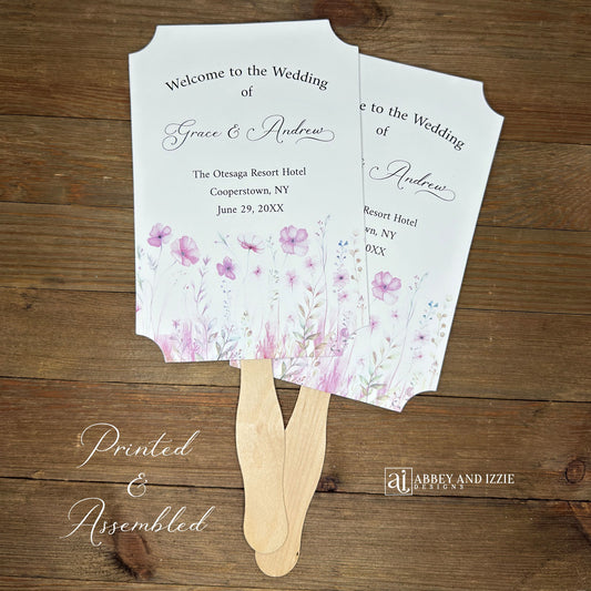 Blush pink wedding fans personalized, printed on white card stock with soft pink flower at the bottom.  Fans are personalized for the bride and groom and includes, place, city, state and date of your wedding.  They arrive fully assembled and ready for your day.