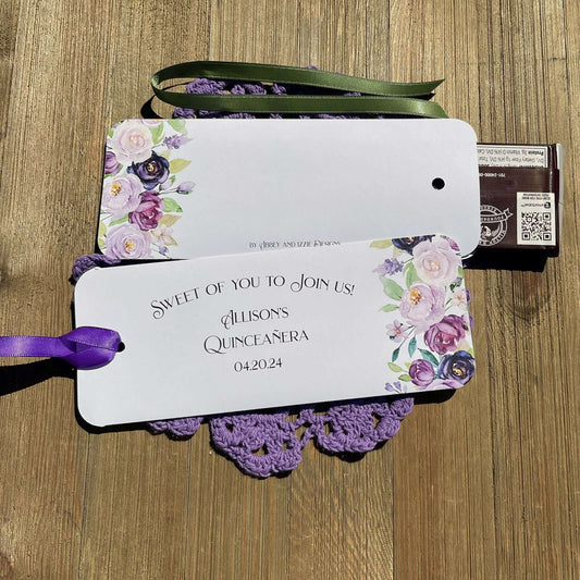 Personalized Quinceanera Candy Favors printed on white card stock and adonred with purple flowers.  Each printed with 'sweet of you to join us' with the guest of honors name and event date.  Slide a candy bar in the open end and tie the ribbon on, your choice of purple or moss green ribbon.