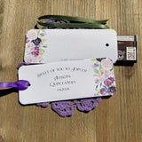 Personalized Quinceanera party favors printed on white card stock and adonred with purple flowers.  Each printed with 'sweet of you to join us' with the guest of honors name and event date.  Slide a candy bar in the open end and tie the ribbon on, your choice of purple or moss green ribbon.