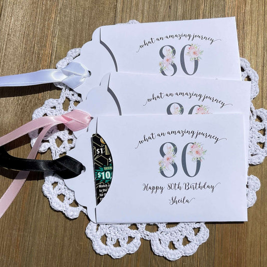 Milestone 80th Birthday Party Favors,  white envelopes adorned with 80 in a floral design, personalized for the guest of honor.