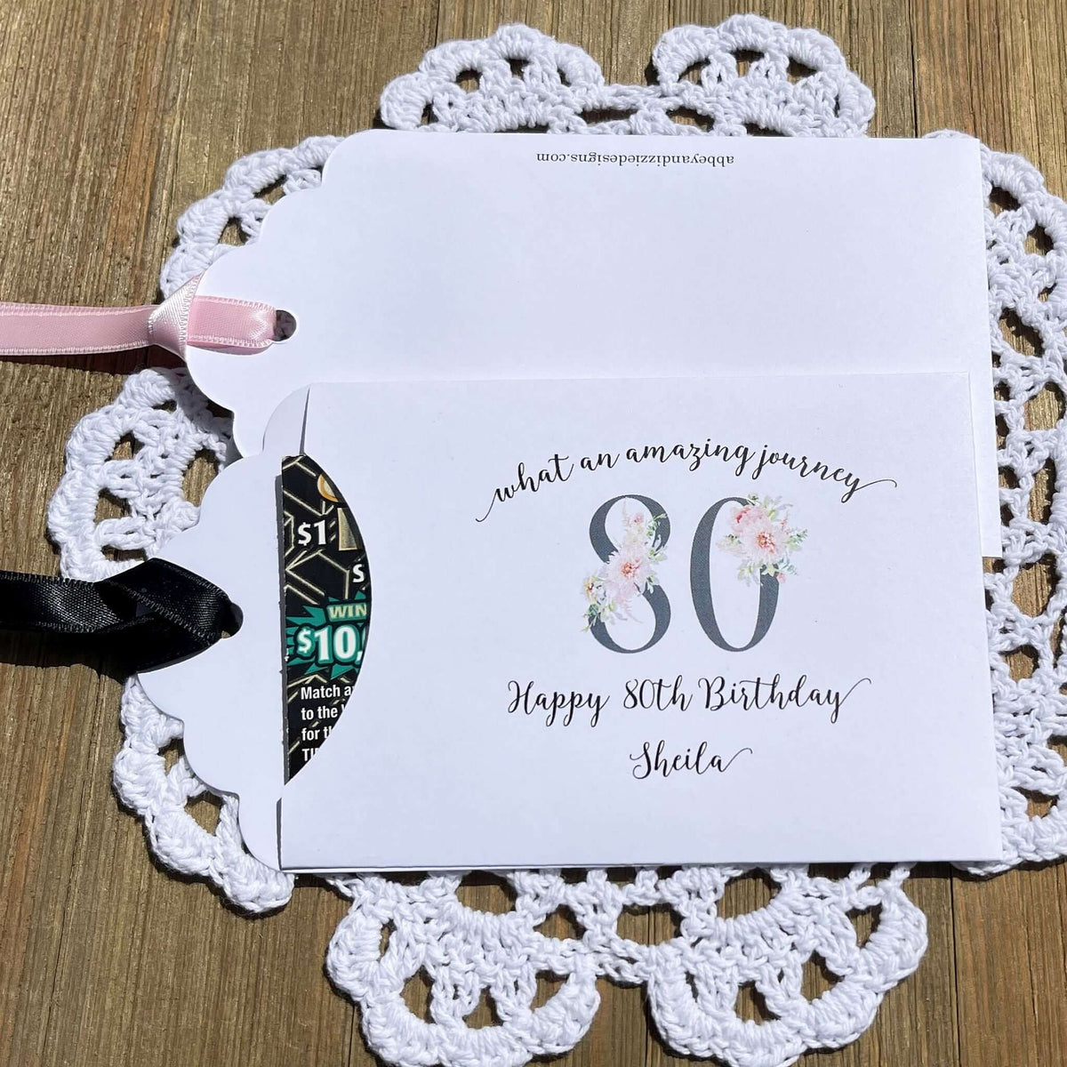 Milestone 80th Birthday Party Favors,  white envelopes adorned with 80 in a floral design, personalized for the guest of honor.