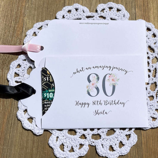 Milestone 80th Birthday Party Favors,  white envelopes adorned with 80 in a floral design, personalized for the guest of honor.