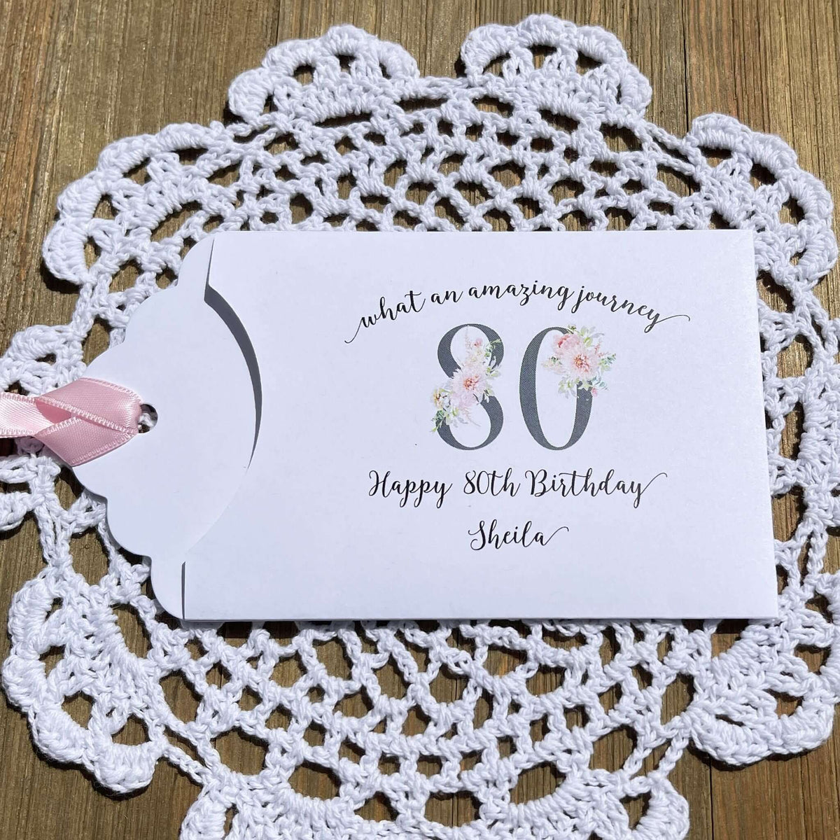 Milestone 80th Birthday Party Favors,  white envelopes adorned with 80 in a floral design, personalized for the guest of honor.