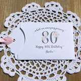 Lottery ticket envelopes for 80th birthday party favors. White envelopes adorned with 80 in a floral design, personalized for the guest of honor.