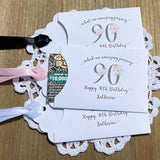 These elegant 90th birthday favors will add a special touch to your event.  Printed on white card stock with a large 90 in floral font add the guest of honors name for a personal touch.  Your choice of pink, black or white ribbon which comes attahced.
