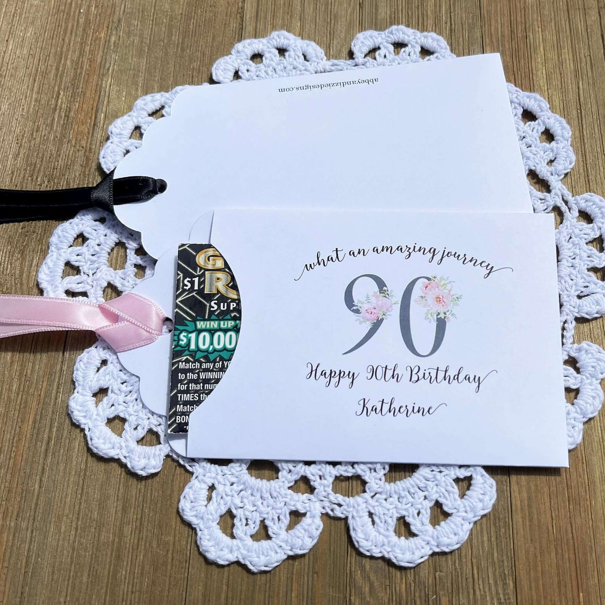 Elegant 90th Birthday Party Favors will add a special touch to your event.  Printed on white card stock with a large 90 in floral font add the guest of honors name for a personal touch.  Your choice of pink, black or white ribbon which comes attahced.