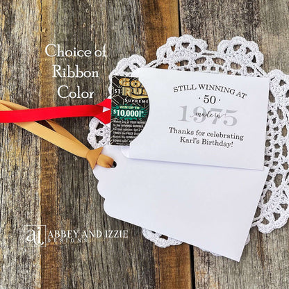 Lottery Ticket Birthday Favors, slide a lottery ticket in these cute envelopes for a fun favor.  Printed with 'still winning at' with your birthday number and year.  Printed on white card stock with your choice of ribbon color.