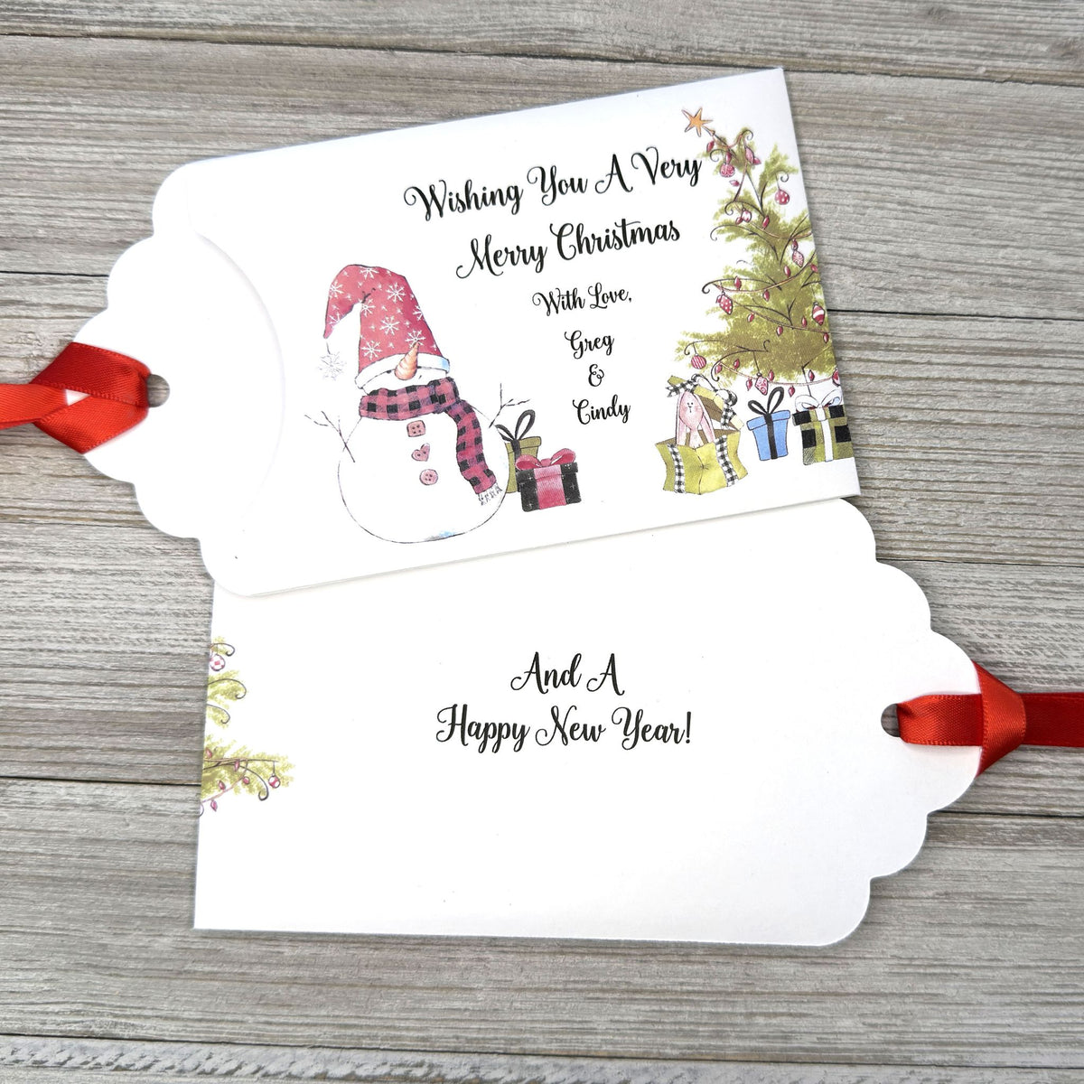 Small Christmas gift lottery ticket envelopes, give your guests a chance to win big. Enclose a scratch off lotto ticket, just a little something to remember friends or co-workers this Holiday Season.  Envelopes are made from white cardstock with a snowman, Christmas tree and gifts.  Personalized with wishing you a Very Merry Christmas. Red ribbon comes attached.