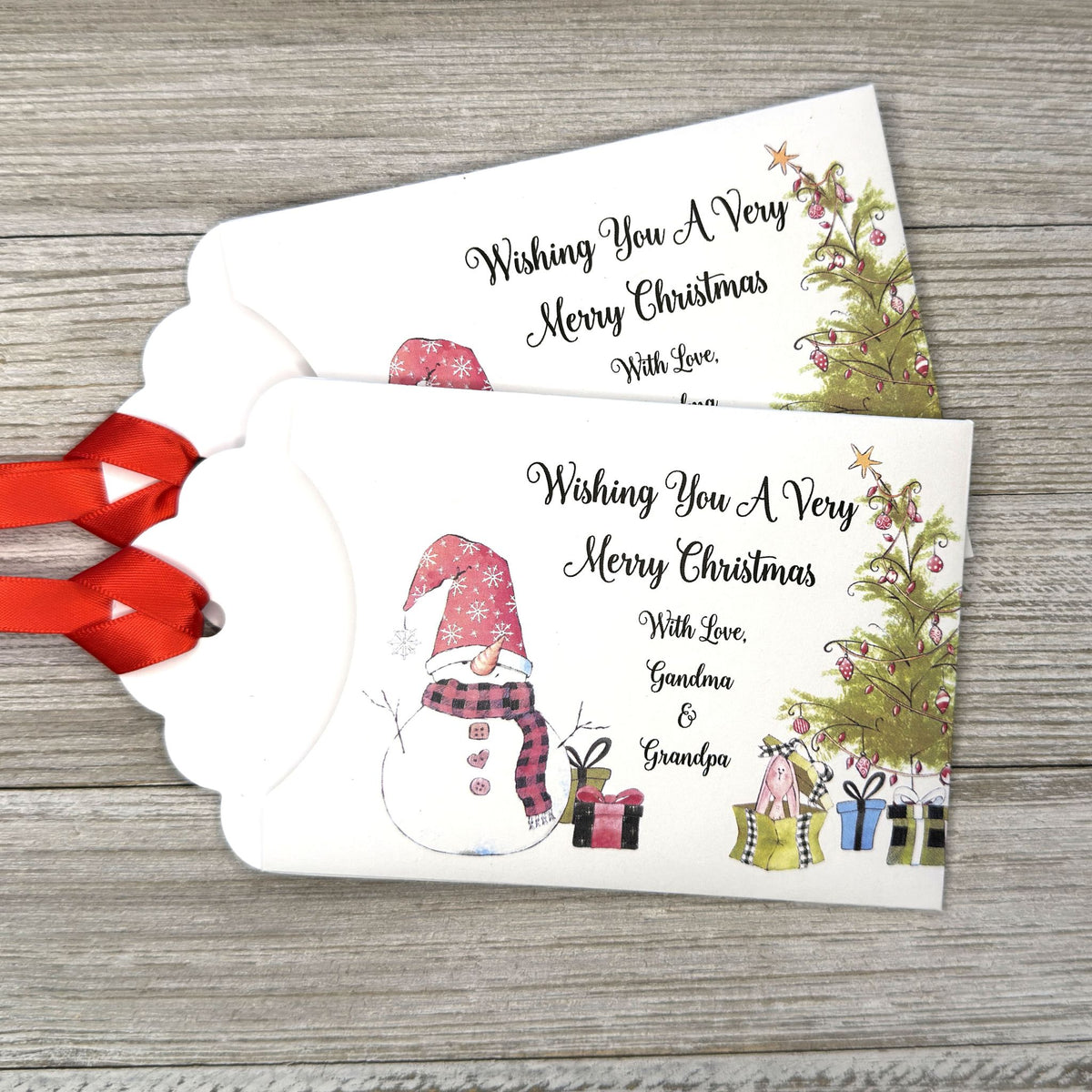Small Christmas gift lottery ticket envelopes, give your guests a chance to win big. Enclose a scratch off lotto ticket, just a little something to remember friends or co-workers this Holiday Season.  Envelopes are made from white cardstock with a snowman, Christmas tree and gifts.  Personalized with wishing you a Very Merry Christmas. Red ribbon comes attached.