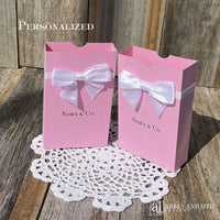 Pink favor boxes personalized for the guest of honor.  Made from pink card stock with white ribbon and bow around the top which comes attached. 