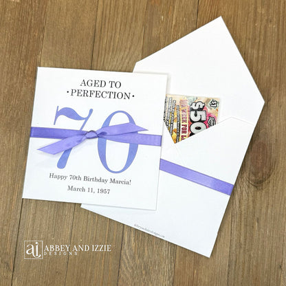 These interactive Aged to Perfection scratch-off holders transform birthday celebrations into memorable moments. Guests scratch off the lottery ticket inside to reveal who the big winner is!&nbsp; Perfect for 50th, 60th, 70th birthdays, available for any birthday. Fully customizable with name, dates, and special messages tailored to the guest of honor. Printed on sturdy white cardstock ensures durability throughout your party. Your choice of large number color as well as the ribbon color to match your party