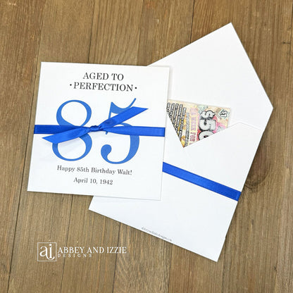 These interactive Aged to Perfection scratch-off holders transform birthday celebrations into memorable moments. Guests scratch off the lottery ticket inside to reveal who the big winner is!&nbsp; Perfect for 50th, 60th, 70th birthdays, available for any birthday. Fully customizable with name, dates, and special messages tailored to the guest of honor. Printed on sturdy white cardstock ensures durability throughout your party. Your choice of large number color as well as the ribbon color to match your party
